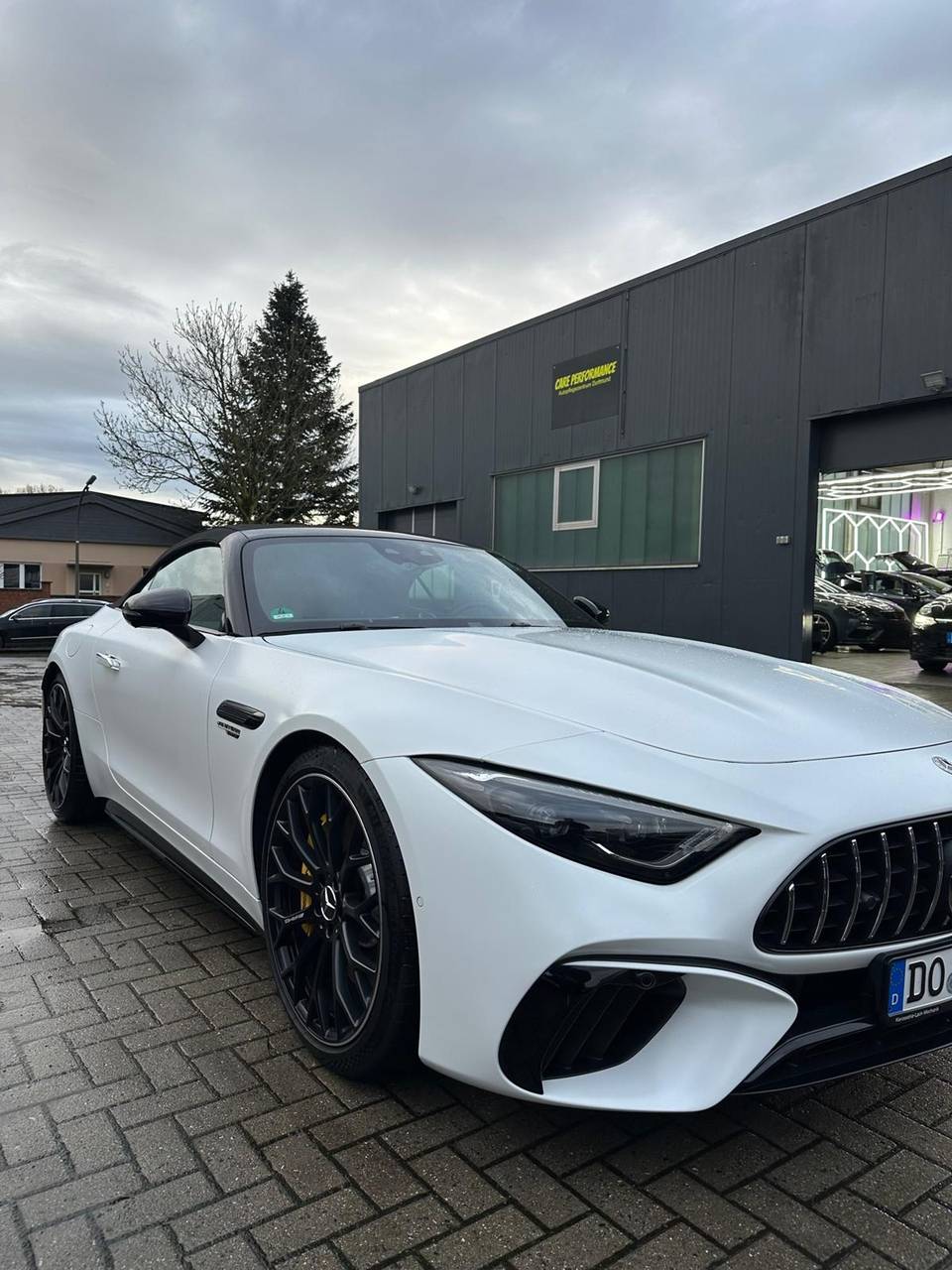 Weißer Mercedes-AMG SL vor der Halle von Care Performance in Dortmund-Eving